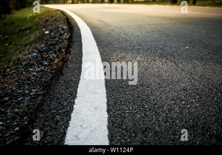 Courbe blanche road line sur l'asphalte marbre avec effet de lumière et soleil soft focus sélectif, notion d'entreprise ou les voyages. Banque D'Images