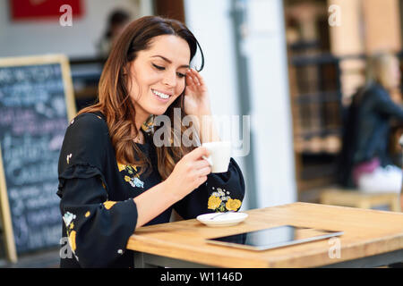 Middle-aged woman drinking coffee in an urban bar café. Banque D'Images