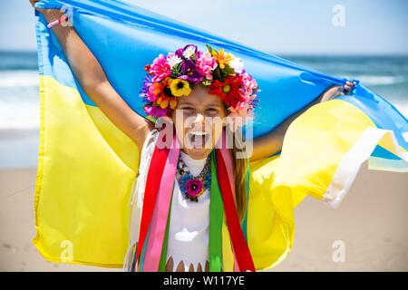 Heureuse jeune fille ukrainienne est titulaire du pavillon bleu et jaune de l'Ukraine contre le ciel bleu et la mer arrière-plan. Pavillon ukrainien est un symbole de l'indépendance Banque D'Images