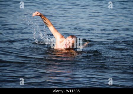 Homme adulte avec une barbe weary nage dans une mer bleu orageux, copyspace Banque D'Images
