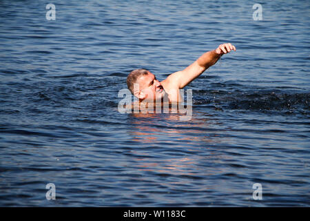 Homme adulte avec une barbe weary nage dans une mer bleu orageux, copyspace Banque D'Images