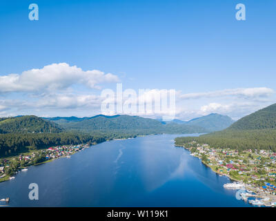 Vue aérienne de l'embouchure dans le lac Teletskoye large dans les montagnes de l'Altaï par l'eau, bleu ciel avec des nuages blancs, vert des arbres sur les pentes de l'un des roches Banque D'Images