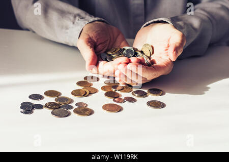 Pièces dans old woman's hands on white background with copy space Banque D'Images