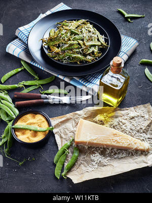 Rôties et polenta croustillante au parmesan panés Frites de pois mange-tout servi sur un plateau. Ingrédients sur une table en béton, vertical Vue de dessus Banque D'Images