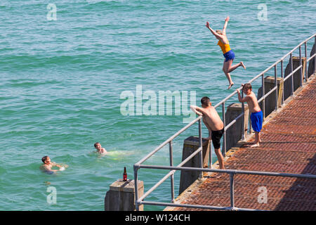 Bournemouth, Dorset, UK. 29 Juin, 2019. Météo France : brulante et ensoleillée à plages de Bournemouth, en tant que chef de la mer sunseekers pour profiter du beau temps. En milieu d'après-midi et les personnes fréquentant les plages encore arriver à trouver un espace, à la fois dans les parcs et sur les plages avec des paniers à peine une zone de réserve de sable en vue sur la journée la plus chaude de l'année jusqu'à présent. Malgré les signes d'eau peu profonde et de ne pas plonger ou encore jeunes saut sautez le pas ! Désactivation de la jetée de Bournemouth. Credit : Carolyn Jenkins/Alamy Live News Banque D'Images