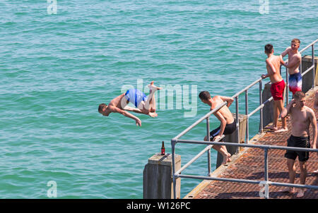 Bournemouth, Dorset, UK. 29 Juin, 2019. Météo France : brulante et ensoleillée à plages de Bournemouth, en tant que chef de la mer sunseekers pour profiter du beau temps. En milieu d'après-midi et les personnes fréquentant les plages encore arriver à trouver un espace, à la fois dans les parcs et sur les plages avec des paniers à peine une zone de réserve de sable en vue sur la journée la plus chaude de l'année jusqu'à présent. Malgré les signes d'eau peu profonde et de ne pas plonger ou encore jeunes saut sautez le pas ! Désactivation de la jetée de Bournemouth. Credit : Carolyn Jenkins/Alamy Live News Banque D'Images