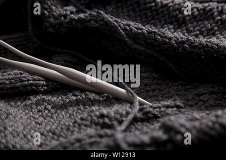 Deux aiguilles dans un projet de tricot gris entre Banque D'Images