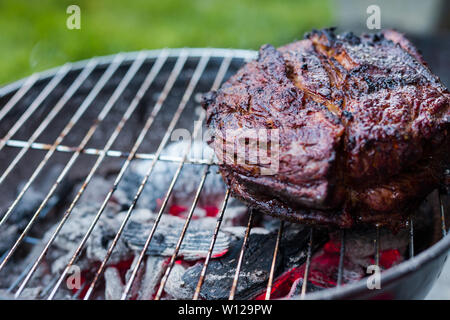 Un grand de poitrine et d'être sur un petit barbecue grill chaufferette avec braise en dessous. Banque D'Images