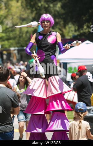 Une femme marche sur pilotis jongle pour les clients qui fréquentent le Festival annuel de la crème glacée d'Atlanta le 28 juillet 2018 à Atlanta, GA. Banque D'Images