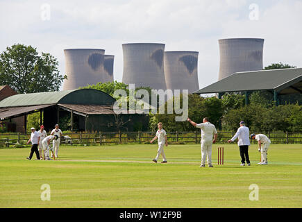 Match de cricket en cours dans le village de Drax, dominé par les tours de refroidissement de Drax Power Station, North Yorkshire, England UK Banque D'Images