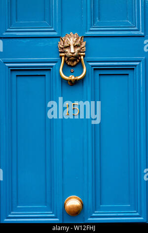 Numéro de maison 15 avec le 15 en jaune vif sur une porte avant en bois bleu et lions head heurtoir ouvragé Banque D'Images