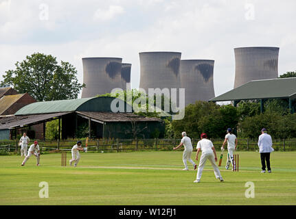 Match de cricket en cours dans le village de Drax, dominé par les tours de refroidissement de Drax Power Station, North Yorkshire, England UK Banque D'Images