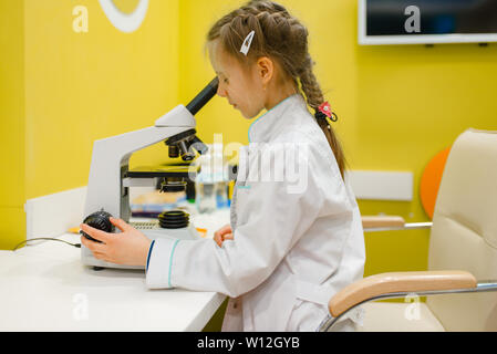 Fille au microscope, jouant médecin, salle de jeux Banque D'Images