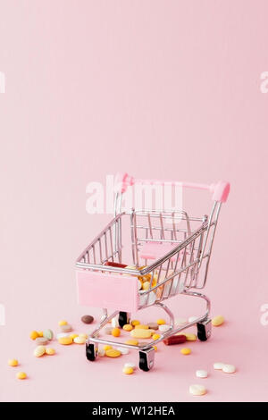 Panier du supermarché plein de pilules et drogues sur un fond rose. Les achats de médicaments, l'achat sur Internet. Télévision Banque D'Images