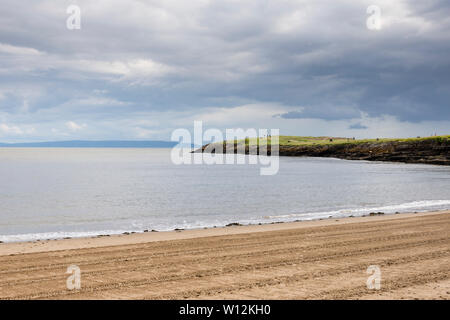 Soleil brille pendant une pause dans les nuages sur la plage de sable de l'île de Barry, rayée par les traces de pneus du tracteur, et le frère de faible altitude's point pointe. Banque D'Images