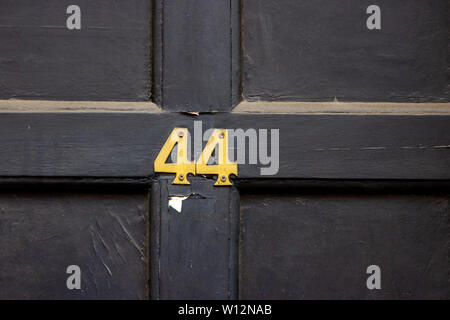 Numéro de maison 44 avec les quarante-quatre chiffres en métal sur une porte en bois Banque D'Images