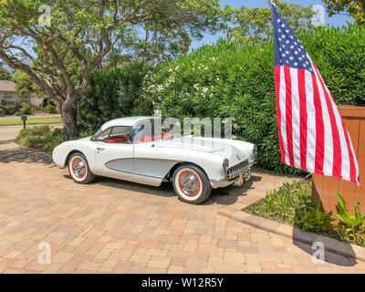 Vue latérale d'un blanc à l'argent 1957 Corvette avec le toit rigide en option avec le drapeau américain à l'avant du véhicule. Banque D'Images