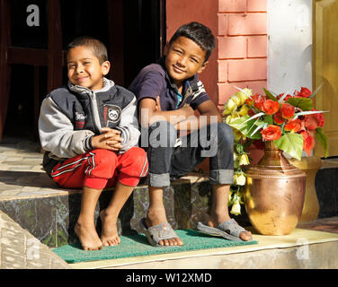 Deux jeunes garçons s'asseoir sur l'étape de café dans la ville historique de Newari trading post ville de Bandipur, Tanahan District, Népal Banque D'Images