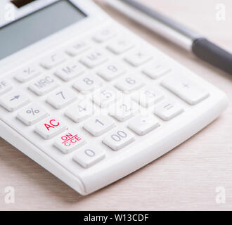 Calculatrice et stylo blanc sur la table en bois clair, analytique et statistique de profit financier, le risque d'investissement concept, copy space, macro, Close up Banque D'Images