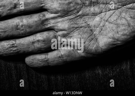 Image noir et blanc d'hommes âgés ayant les mains sur un fond sombre. Détail de la paume de la main. Banque D'Images