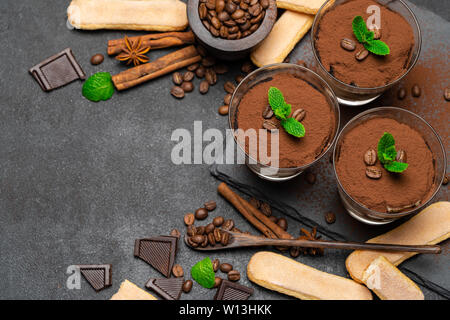 Cadre fait de dessert tiramisu classique dans un verre et savoiardi cookies sur fond de béton foncé Banque D'Images