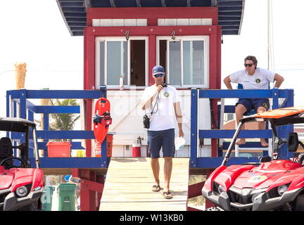 Deux hommes des maîtres nageurs à Cocoa Beach, l'une descend de la gare de parler sur une radio et d'autres l'un est assis sur un piédestal à l'extérieur. Banque D'Images