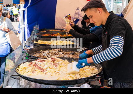 Vue le long de l'homme en remuant Grande Casserole de pommes de terre à la crème sur le marché français de la nourriture chaude, wc séparés avec d'autres pans de l'alimentation, dans la ville anglaise, Sandwich. Banque D'Images