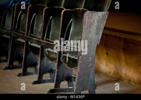 Chaise pliante en bois miteux dans la rangée debout dans une pièce sombre Banque D'Images