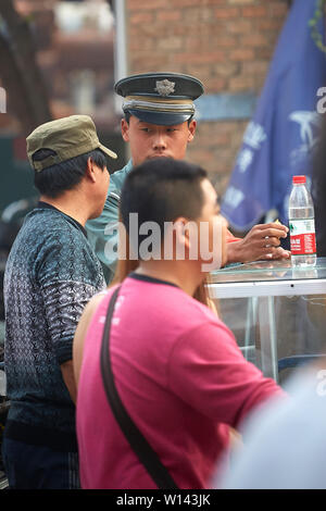 Un policier chinois parler comme il prend sa pause déjeuner dans la 798 Art Zone, Beijing, République populaire de Chine. Banque D'Images