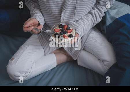 Femme au lit de manger du gruau d'avoine avec des baies sauvages. Banque D'Images