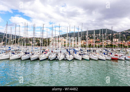 Voiliers parfaitement dans une ligne dans le port et maisons sur les collines, contre ciel nuageux à Lerici en Ligurie, Italie Banque D'Images