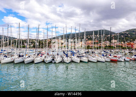 Voiliers parfaitement dans une ligne dans le port et maisons sur les collines, contre ciel nuageux à Lerici en Ligurie, Italie Banque D'Images