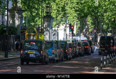 Longue file de taxis à l'extrémité ouest de la cage à pied dans le centre de Londres, à l'arrêt aux feux de circulation Banque D'Images