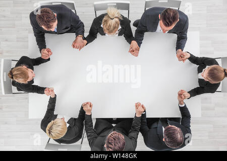 L'équipe d'affaires se tenant la main autour de la table, vue du dessus , l'espace de copie pour le texte Banque D'Images