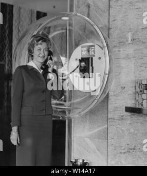 Téléphoner dans les années 1950. Un employé d'un Palace Hôtel montre le nouveau téléphone de courtoisie installés dans le hall. Téléphone dans les années 1950. Elle porte une robe typique 50s et d'avoir une conversation téléphonique. Le dôme en acrylique est un design fonctionnel où la personne qui parle, n'est pas d'être surpris par quelqu'un et aussi le blocage de l'arrière-plan environnant noice. Suède 1950 Banque D'Images