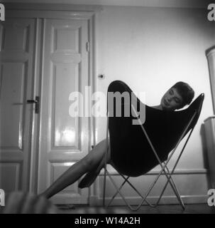 Maison des années 50. La jeune actrice Margit Carlqvist est assis dans un années 1950, papillon populaire président, également connu sous le nom de BKF chaise ou fauteuil Hardoy. Suède 1955. Kristoffersson ref br53-7 Banque D'Images