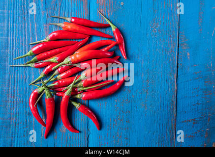 Vue de dessus rouge mûre petits piments rouges sur fond bleu en bois ancien avec l'exemplaire de l'espace pour votre texte. Banque D'Images