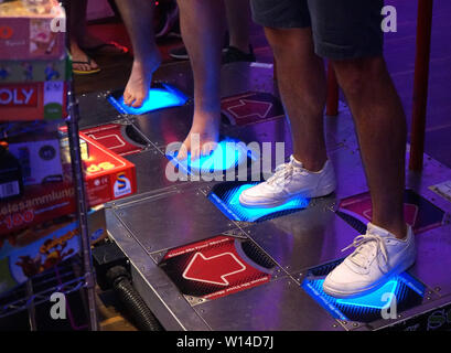 29 juin 2019, en Rhénanie du Nord-Westphalie, Krefeld : Visiteurs dance à l'e-sport 'tournoi Homestory Cup' jouer le jeu d'arcade Dance Dance Revolution'. Deux fois par an les meilleurs joueurs de la discipline e-sports Starcraft 2 sont tirées de Krefeld. 32 meilleurs joueurs du monde entier viennent au 'Homestory Cup' à participer à améliorer la discipline. (Dpa 'champion du monde de bar ambiance à l'e-sports 'tournoi Homestory Cup') Photo : Benedikt Wenck/dpa Banque D'Images