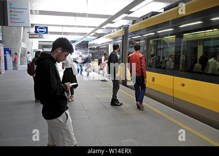 Young man wearing earphones à son iphone à l'écoute de la musique, envoyer des sms dans le métro gare Porto Porto Portugal Europe KATHY DEWITT Banque D'Images