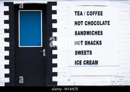 Café thé café servant des sandwiches et des collations chaudes douceurs glaces signe sur mur blanc Banque D'Images