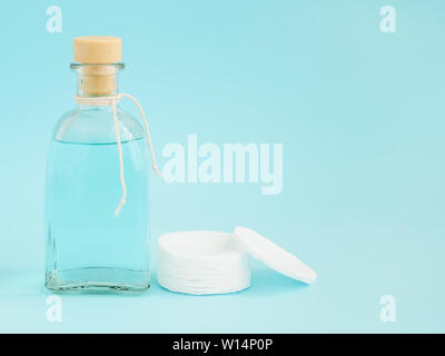 Tonique pour la peau visage démaquillant ou dans une bouteille de verre et coton sur fond bleu pastel. Fournitures d'hygiène, de beauté et d'outils de soins de la peau. Copie Banque D'Images