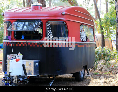 Concept de vacances. Petite remorque de camping rétro noir et rouge sur la nature. Banque D'Images