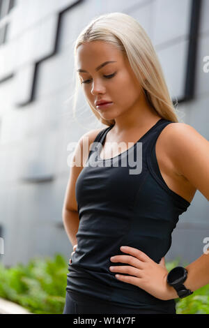 Close-up of fit woman repose avec les mains sur les hanches en ville Banque D'Images