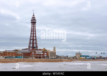 BLACKPOOL, Royaume-Uni, le 30 juin 2019 : La tour de Blackpool est au-dessus de vagues qui se présentent durant la marée haute sur un jour nuageux. Banque D'Images