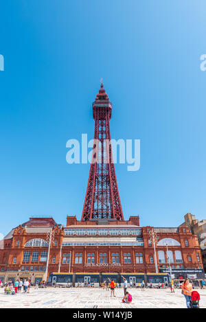 BLACKPOOL, Royaume-Uni, le 30 juin 2019 : les touristes se rassemblent et se détendre en face de la tour de Blackpool sur le tapis comme une comédie passe par le tramway électrique. Banque D'Images