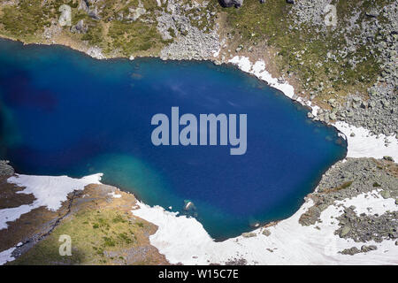 Colorés, Close up Vue de dessus de la Twin Lake sur la montagne de Rila avec une profonde, bleu saphir d'eau et de neige paysage rocheux couverts Banque D'Images