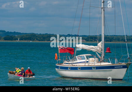 Dans la famille petit canot laissent leurs Hallberg-Rassy location ancrée jusqu'à aller à terre au large de la tête dans le port de Chichester, West Sussex, England, UK Banque D'Images