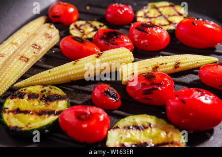 Légumes grillés sur le poêle. Courgettes, mini-maïs, tomate cerise Banque D'Images