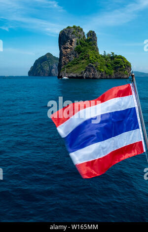 Un portrait d'un marin d'une petite île thaïlandaise de calcaire dans les eaux scintillantes de la mer d'Andaman, avec le drapeau de la Thaïlande palpitations dans l'foregro Banque D'Images