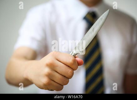 Teenage school boy holding a knife Couteau pour illustrer la criminalité dans les écoles britanniques Banque D'Images